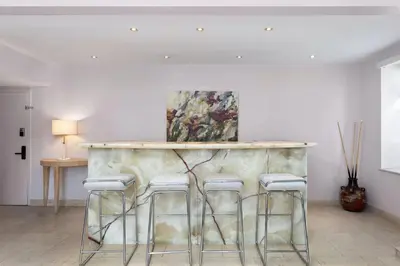 a bar with four stools in a room with a painting at Roami at Hotel Astor in Miami Beach