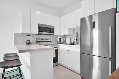 a kitchen with white cabinets and a stainless steel refrigerator at Villa 2 in Miami in Miami