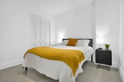 a white bedroom with a large bed with a yellow blanket at Villa 2 in Miami in Miami