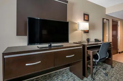 a hotel room with a desk with a flat screen tv at Comfort Suites Fort Lauderdale Airport South & Cruise Port in Dania Beach