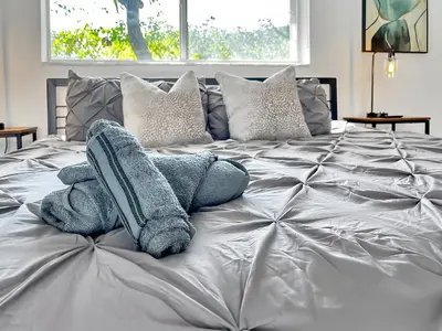 a bed with gray blankets and pillows on it at Gated Villa Blanca 5BR 3BA with Heated Pool & BBQ in Miami