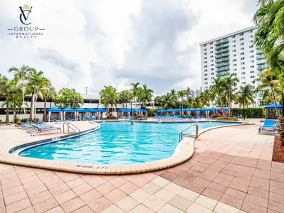 a pool at a resort with palm trees and a building at Comfortable and broad apartment in O-Reserve near on the beach in Sunny Isles Beach
