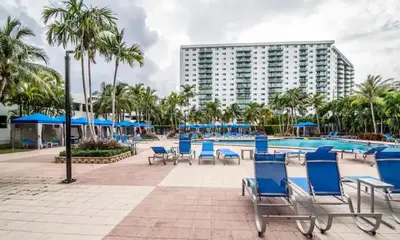 a pool with blue chairs and a large building at Comfortable and broad apartment in O-Reserve near on the beach in Sunny Isles Beach