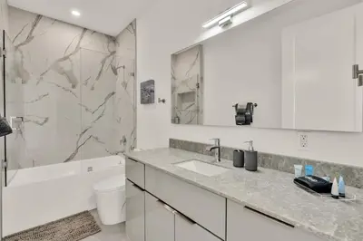 a white bathroom with a sink and a tub at Ocean Wave Deluxe Brand New Apartments in Fort Lauderdale