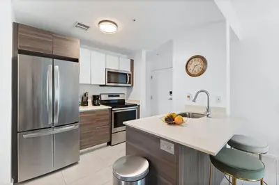 a kitchen with a stainless steel refrigerator and stools at Modern apartment in Edgewater in Miami