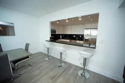 a kitchen with a bar with stools and a table at Spacious apartment of 2BR - 2BTH in Ocean Reserv front the beach in Sunny Isles Beach