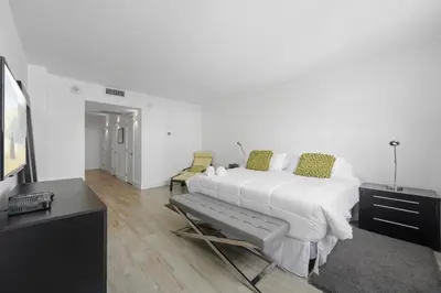 a white bedroom with a large bed and a tv at Spacious apartment of 2BR - 2BTH in Ocean Reserv front the beach in Sunny Isles Beach