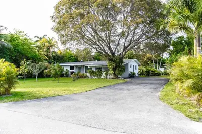 a house with a tree in front of a driveway at Tropical Private Oasis Mins from Beach & Downtown in Miami