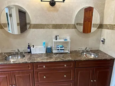 a bathroom with two sinks and two mirrors at Cozy lakeside suite with private bath & entrance in Pembroke Pines