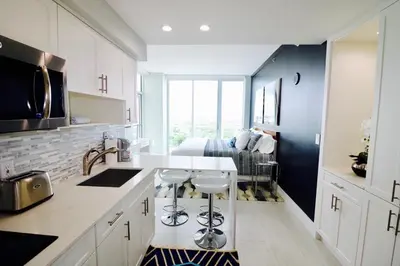 a kitchen with white cabinets and a sink and a bedroom at Connecting Rooms-Coconut Grove 21st Floor Parking Included in Miami