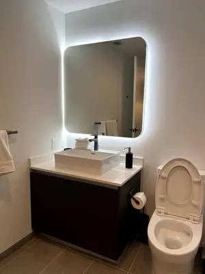a bathroom with a sink and a toilet with a mirror at Modern Studio Downtown with Pool and Gym in Miami