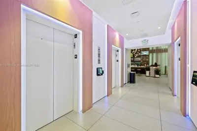 a hallway with white doors and pink walls at Ocean View Cozy Studio Pool and Gym in Miami