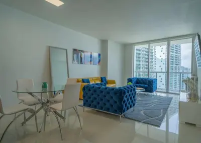 a living room with a glass table and blue chairs at Deluxe Suite King 1 Bedroom Icon in Miami