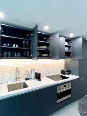 a kitchen with dark blue cabinets and a sink at Upscale Ocean View Studio Pool and Gym in Miami