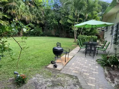 a grill sitting on a brick patio with a table and umbrella at Tropical Classic Retro Florida, Private 2 bedroom Suite with Best Location in Fort Lauderdale