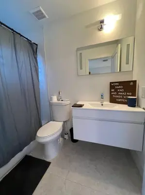 a bathroom with a toilet and a sink and a mirror at Super stylish 4 BR Home Steps from the Fun in Fort Lauderdale