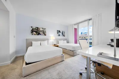 a hotel room with two beds and a desk at Beachwalk Studio (Beach, Pool and Gym) in Hallandale Beach