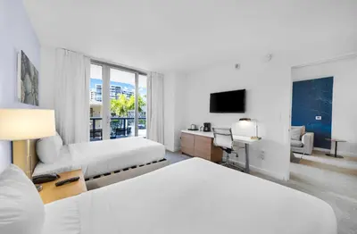 a hotel room with two beds and a television at Beachwalk Studio (Beach, Pool and Gym) in Hallandale Beach