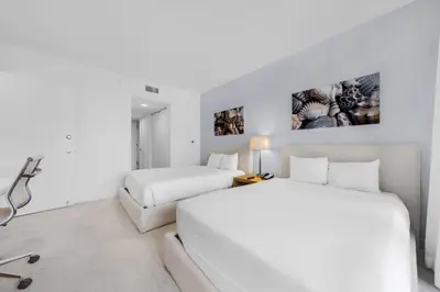 two beds in a bedroom with white walls at Beachwalk Studio (Beach, Pool and Gym) in Hallandale Beach