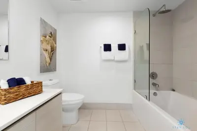 a white bathroom with a toilet and a shower at Upper Beachwalk Condo Amazing Balcony View in Hallandale Beach