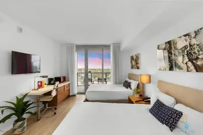 a hotel room with two beds and a desk at Beachwalk Studio Amazing View Pininfarina Design in Hallandale Beach