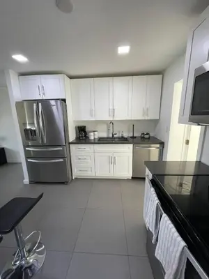 a kitchen with white cabinets and a stainless steel refrigerator at Stylish Pool Home in Hollywood
