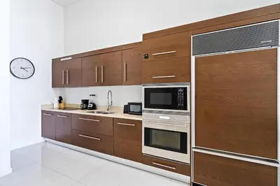 a kitchen with wooden cabinets and a clock on the wall at Icon 1 Bed With Water Views 16 ft Ceilings and Free Spa Access in Miami