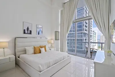 a white bedroom with a bed and a large window at Icon 1 Bed With Water Views 16 ft Ceilings and Free Spa Access in Miami