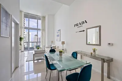 a living room with a glass table and blue chairs at Icon 1 Bed With Water Views 16 ft Ceilings and Free Spa Access in Miami
