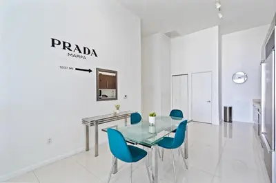 a dining room with a glass table and blue chairs at Icon 1 Bed With Water Views 16 ft Ceilings and Free Spa Access in Miami