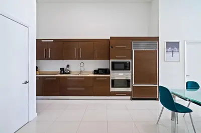 a kitchen with wooden cabinets and a table and a blue chair at Icon 1 Bed With Water Views 16 ft Ceilings and Free Spa Access in Miami