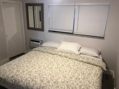 a bedroom with a bed with a comforter and a window at City First Story Apartments & Cottage in Fort Lauderdale