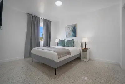 a white bedroom with a bed and a window at Elegant Wynwood Flats in Miami