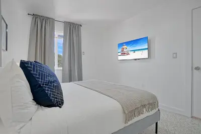 a white bedroom with a bed and a window at Elegant Wynwood Flats in Miami