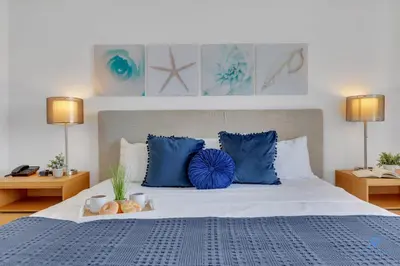 a bedroom with a large bed with blue pillows at Prime Location Amazing Pool Balcony Bay View in Hallandale Beach