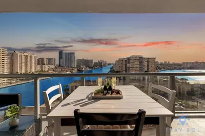 a table on a balcony with a view of the water at South Beach Retreat Balcony Resort Amenities in Hallandale Beach