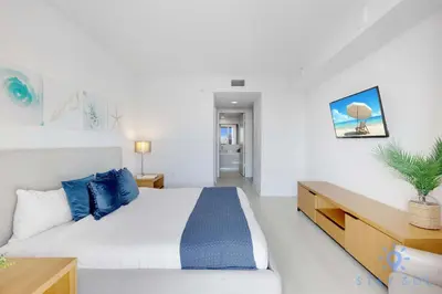 a bedroom with a large bed with blue pillows at South Beach Retreat Balcony Resort Amenities in Hallandale Beach