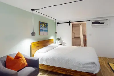 a bedroom with a large bed and a chair at Walking On Sunshine - Studio in Fort Lauderdale