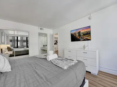 a white bedroom with a large bed and a bathroom at Awesome Beach Condo with Resort Amenities 1016 in Miami Beach