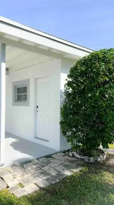 a white house with a white door and a bush at Cozy apartment near Seminole Hard Rock Cafe in Hollywood