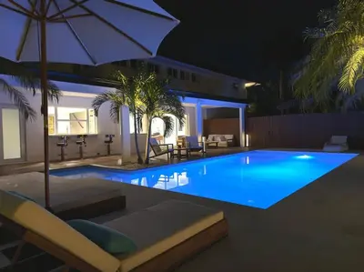 a swimming pool at night with an umbrella and chairs at Villa Santa Maria in Cutler Bay
