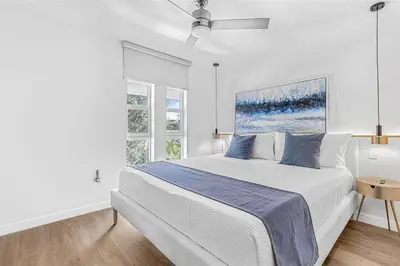 a white bedroom with a large bed and a window at Villa Santa Maria in Cutler Bay