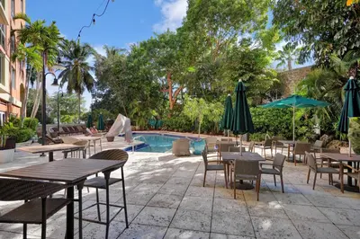 a patio with tables and chairs next to a pool at Modern Bay View Balcony In The Grove Free Parking in Miami