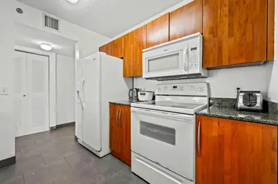 a kitchen with white appliances and wooden cabinets at Luxury 1 BDR • 30th Floor • Brickell • Water Views in Miami