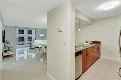 a kitchen with a sink and a living room at Lux 1B condo with XL Balcony, Pool, Gym & Games in Miami