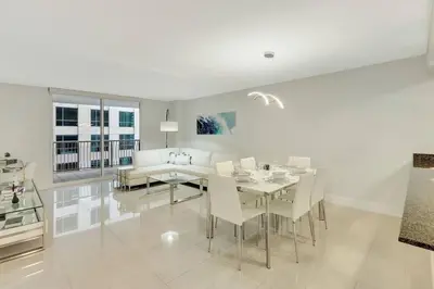 a white dining room with a table and chairs at Lux 1B condo with XL Balcony, Pool, Gym & Games in Miami