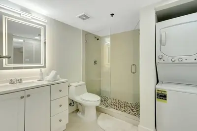 a white bathroom with a toilet and a shower at Lux 1B condo with XL Balcony, Pool, Gym & Games in Miami