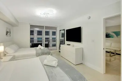 a white room with a bed and a television at Lux 1B condo with XL Balcony, Pool, Gym & Games in Miami