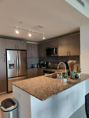 a kitchen with a granite counter top and stainless steel appliances at Stylish 1-Bedroom Getaway Apt- pool & gym in Miami