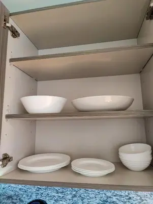 four bowls and plates on shelves in a closet at Stylish 1-Bedroom Getaway Apt- pool & gym in Miami